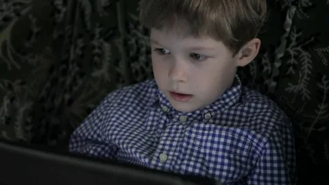 The boy is playing on the tablet, in the evening at home Stock Footage 76426742