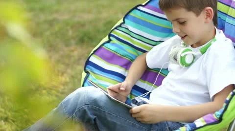 Boy playing with a tablet pc outdoors Stock Footage 11619126
