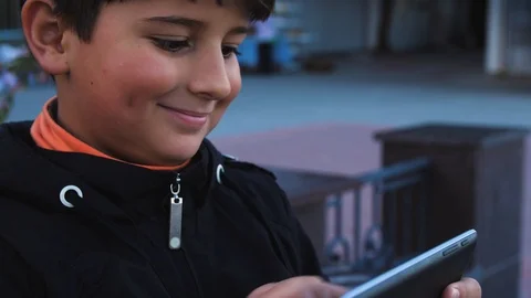 Boy playing on the tablet in the street 스톡 동영상 96575906