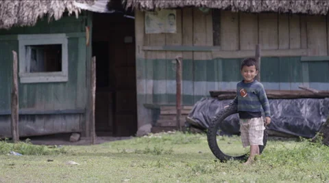 Boy playing with a tire outside a hut in village, Guatemala Stock Footage 63053455