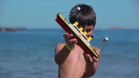 Boy playing with a Titanic ship on the beach Stock Footage 312468679