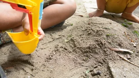 Boy playing with toy backhoe and sand on ground, Stock Footage 83782686