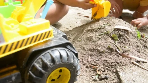Boy playing with toy backhoe and sand on ground, Stock Footage 83782693