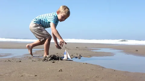 Boy playing with toy boat at beach Stock-Footage 61660163
