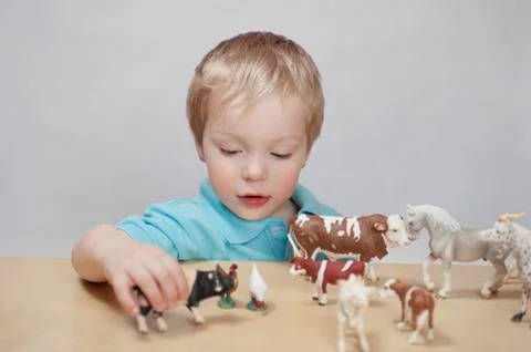 Boy playing with toy farm animals Stock Photos