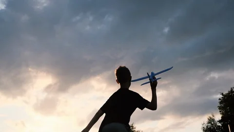 The boy is playing with a toy plane. Sunset. Slow motion. Stock Footage 121205423