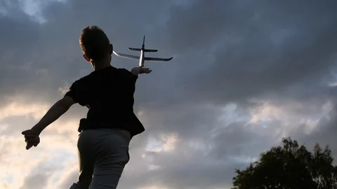 The boy is playing with a toy plane. Sunset. Slow motion. Stock Footage 121205435