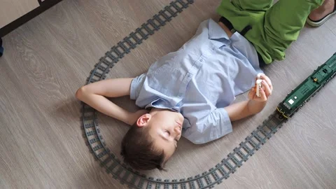 A boy is playing with a train on the controls on the floor in the room. top view Stock Footage 170783412