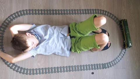 A boy is playing with a train on the controls on the floor in the room. top view Stock Footage 171340851