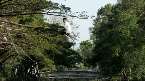A boy playing with tree branch above the polluted river Stock Footage 132450781