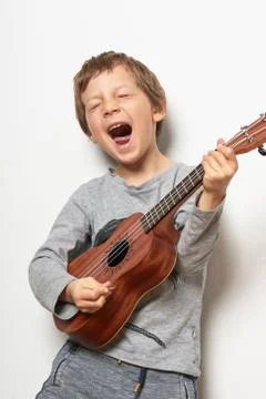 Boy playing ukulele, pulling face 스톡 사진