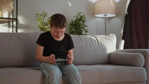 Boy Playing Video Game on Couch. Excited child tablet digital leisure focused Stock Footage 335477987