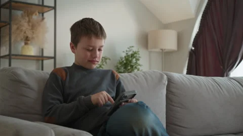 Boy Playing Video Game on Couch. Focused child handheld console digital leisure Stock Footage 335481931