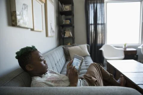 Boy playing video game with digital tablet on sofa Stock Photos