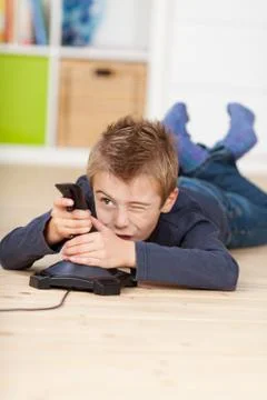 Boy playing video game while lying on floor Foto stock