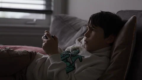 Boy playing video games on couch - medium shot Stock Footage 316199329