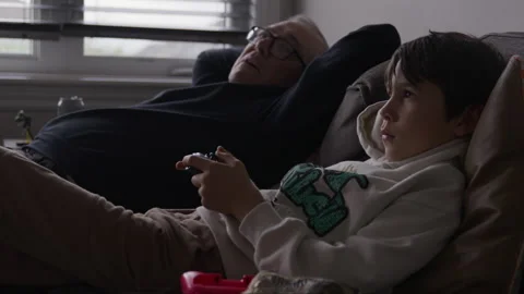 Boy playing video games ignorning grand father sitting beside him Stock Footage 316199255