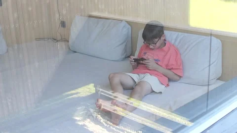 Boy playing video games inside modern tiny house is relaxing on vacation Stock Footage 281971123