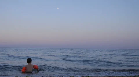 Boy Playing on Waves on the Beach in Inflatable Armbands in Twilight Stock Footage 65402546
