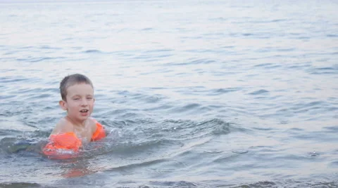 Boy Playing on Waves on the Beach in Inflatable Armbands in Twilight Stock Footage 65402595