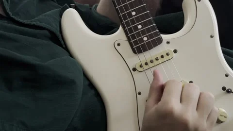 Boy playing a white guitar, focused, casual, outdoor setting, happy. Stock Footage 278593329