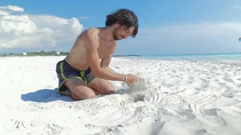A boy playing in the white sand making a hole with her hands Stock Footage 250186060