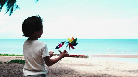 Boy playing windmills outside on the beach together having fun enjoy Stock Footage 199247110