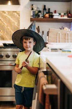 Boy playing wizard in kitchen holding magic wand Stock Photos