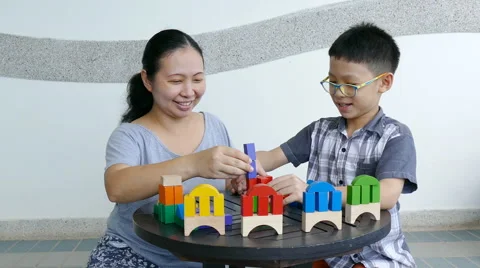 Boy playing with wood blocks on the table with mother Stock Footage 68245818