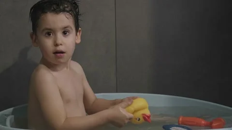 Boy playing with a yellow rubber duck toy while taking a bath. Bathing and Video stock 203770538