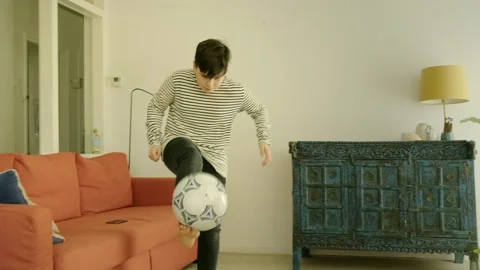 A boy plays with a ball in and around his house Stock Footage 308933488