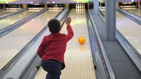 The boy plays bowling. He rolls the ball on the path and falls into the bowling Stock Footage 85921753