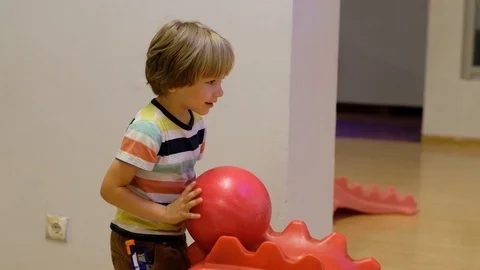 The boy plays bowling. He rolls the ball on the path from a special kids hill Stock Footage 111758841
