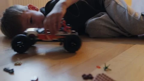 A boy plays with a car that he assembled from a construction set. Stock Footage 252383594