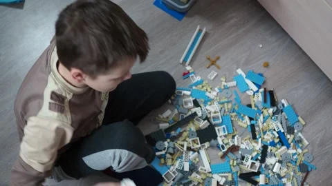 A boy plays a construction kit made of plastic parts on the floor Stock Footage 146857710