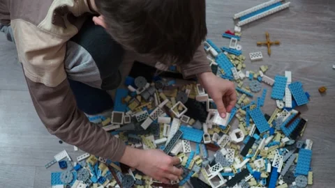 A boy plays a construction kit made of plastic parts on a wooden floor Stock Footage 146909457