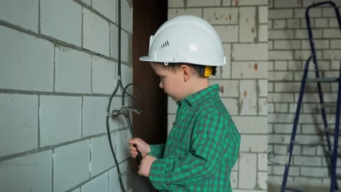A boy plays at a construction site and works with a hammer Stock Footage 238455323