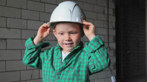 A boy plays construction worker and puts a white helmet on his head Video stock 238353873