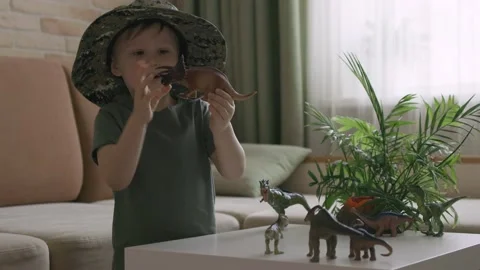 A boy plays with dinosaur figurines on the table. The little explorer in the  Stock Footage 147672594