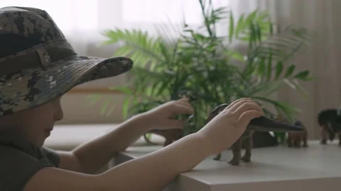 A boy plays with dinosaur figurines on the table. The little explorer in the  Stock Footage 147672926