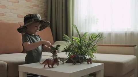 A boy plays with dinosaur figurines on the table. The little explorer in the  Stock Footage 147673270