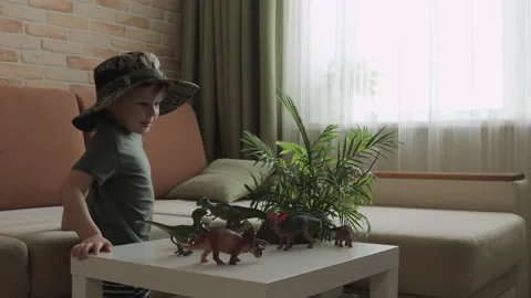 A boy plays with dinosaur figurines on the table. The little explorer in the  Stock Footage 147673453