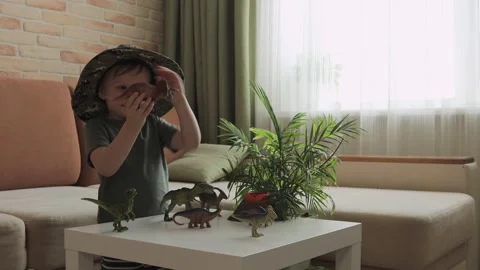 A boy plays with dinosaur figurines on the table. The little explorer in the  Stock Footage 147673486