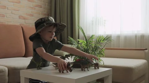 A boy plays with dinosaur figurines on the table. The little explorer in the  Stock Footage 147673528