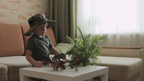 A boy plays with dinosaur figurines on the table. The little explorer in the  Stock Footage 147673862