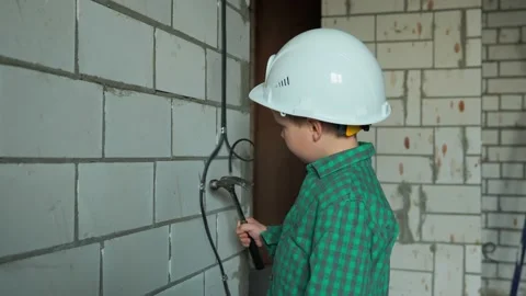 The boy plays engineer and knocks with a hammer on the fastening of wires Stock Footage 238084170