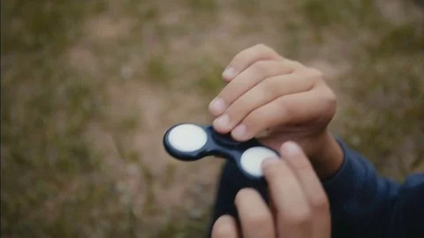 A boy plays with fidget spinner slow motion Stock Footage 76624955