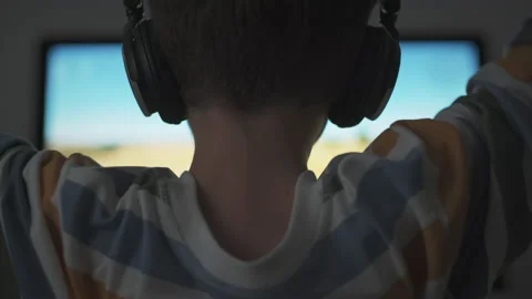 Boy plays game strategy online on computer with headphones in evening in room Stock Footage 133202925