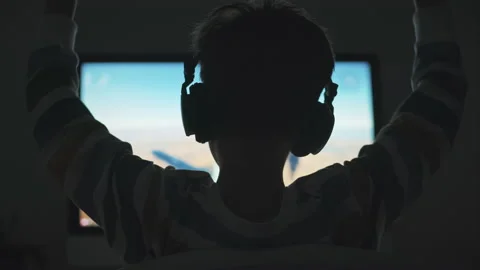 Boy plays game strategy online on computer with headphones in evening in room Stock Footage 133202995