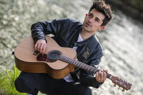 Boy plays guitar by the river Foto stock